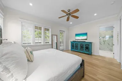 Crisp white bedding, a ceiling fan, and a smart TV, with the bathroom just through the door.