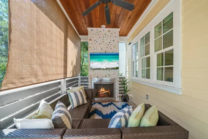 The screened porch is where everyone lands after the beach. Ceiling fans overhead, deep cushioned seating, and nothing but pine woods past the screens.