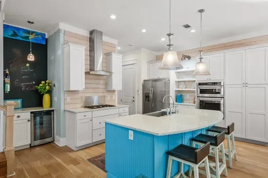 A proper cook's kitchen: gas range under a stainless hood, full size refrigerator, and a deep blue island with room to actually spread out.