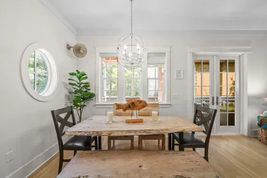 Gather six around the dining table under the chandelier, with the round porthole window throwing light across the room. Steps from the kitchen and the screened porch.