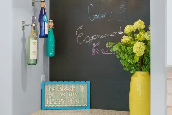The coffee corner, complete with a chalkboard and a standing reminder that the beach is very much your happy place.