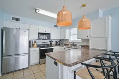 Spacious kitchen in unit B with stainless steel appliances, large island seating, and ample prep space—ideal for group meals and casual dining. Bright coastal finishes and an open layout keep everyone connected to the living area.