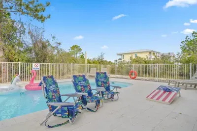 Spacious heated saltwater pool with ample loungers, pool floats, cornhole, and open sun deck. Perfect for relaxing, cooling off, or spending quality time together just steps from the covered picnic and grilling area.
