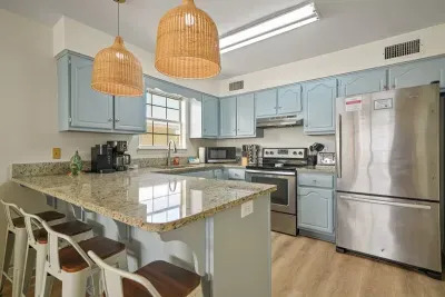 Unit A kitchen showcasing the large island with seating, stainless steel appliances, and generous counter space—perfect for meals, morning coffee, or gathering together.