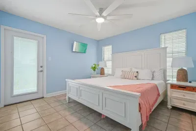 Main-level bedroom on the Unit B side with a comfortable king bed, wall-mounted TV, and private walk-out balcony. Conveniently connected to the shared main-level bathroom and living area—ideal for easy, stair-free access.