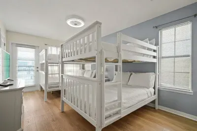 Unit A bunk bedroom featuring queen-over-queen bunks, a private ensuite full bathroom, and a private walk-out balcony. A bright, comfortable space ideal for families or additional guests.