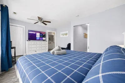 King bed in primary bedroom looking toward the TV and bathroom entrance