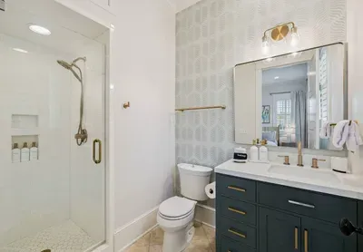 A private ensuite means this bedroom’s guests never share a bath. Walk-in shower, Serena & Lily wallpaper, and starter toiletries already stocked.