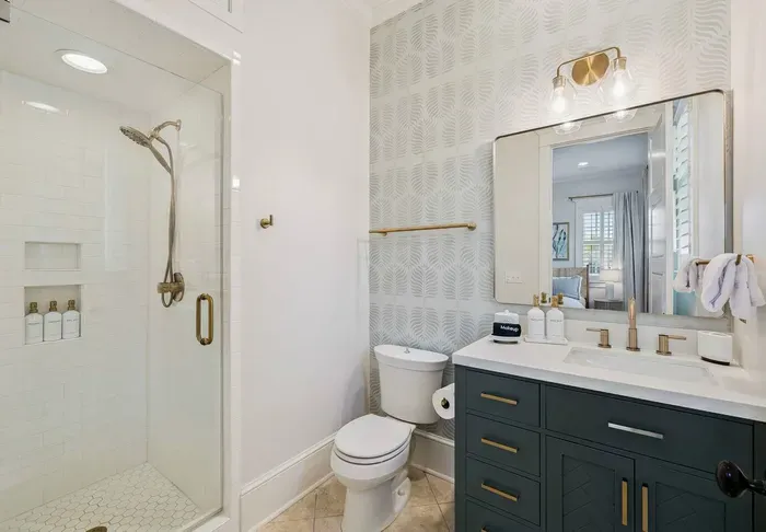A private ensuite means this bedroom’s guests never share a bath. Walk-in shower, Serena & Lily wallpaper, and starter toiletries already stocked.
