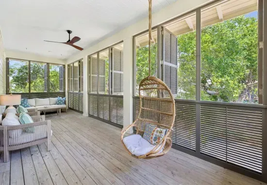 Call the hanging rattan chair early — it’s the most-requested seat in the house. This cozy covered porch stays cool and breezy all day.