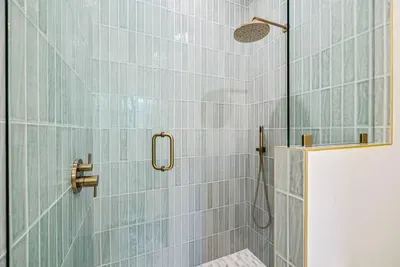 Rinse off the salt and sand under a rainfall showerhead — hand-laid tile and a handheld sprayer make it spa-easy.