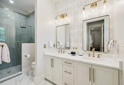 No waiting your turn — a double vanity plus a separate glass shower keep busy mornings moving. Designer wallpaper and bronze fixtures add the wow.