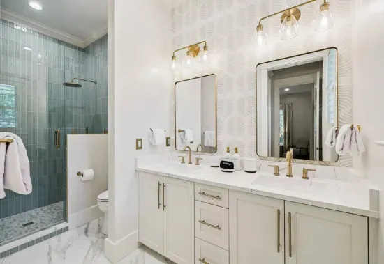 No waiting your turn — a double vanity plus a separate glass shower keep busy mornings moving. Designer wallpaper and bronze fixtures add the wow.
