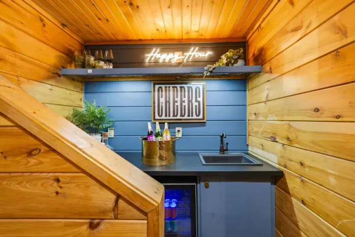 Lower-level wet bar next to the pool room, featuring a “Happy Hour” neon sign.