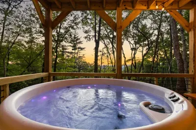 Private forest-view hot tub with a covered deck at sunset