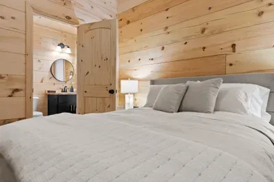 Cozy wood-paneled bedroom with plush hypoallergenic bedding and en-suite bath