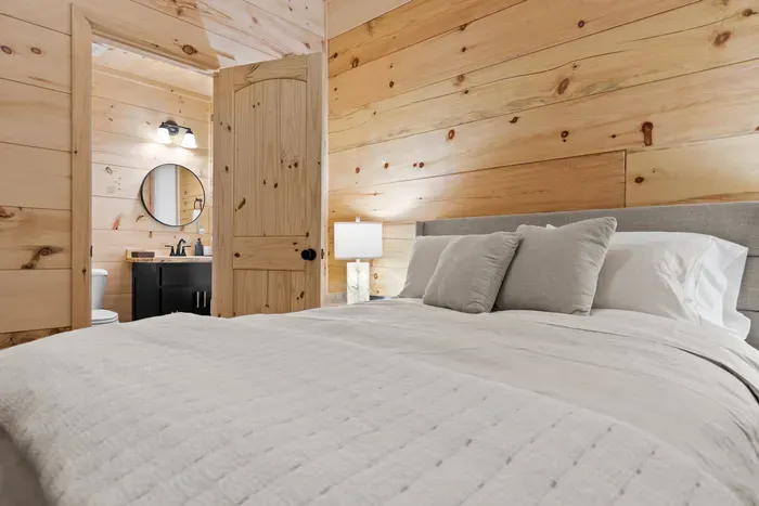 Cozy wood-paneled bedroom with plush hypoallergenic bedding and en-suite bath