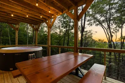 Private covered deck with hot tub, dining table, and serene sunset views. Lower level deck.
