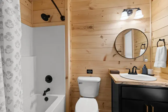 Rustic-modern bathroom with wood accents, tub shower, and stylish vanity. En suite bathroom