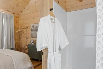 Cozy wood-lined retreat with plush robe and convenient in-room shower with tub.