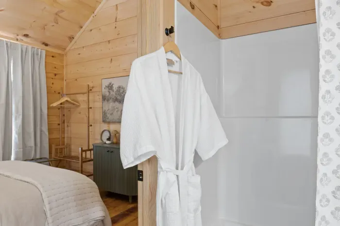 Cozy wood-lined retreat with plush robe and convenient in-room shower with tub.