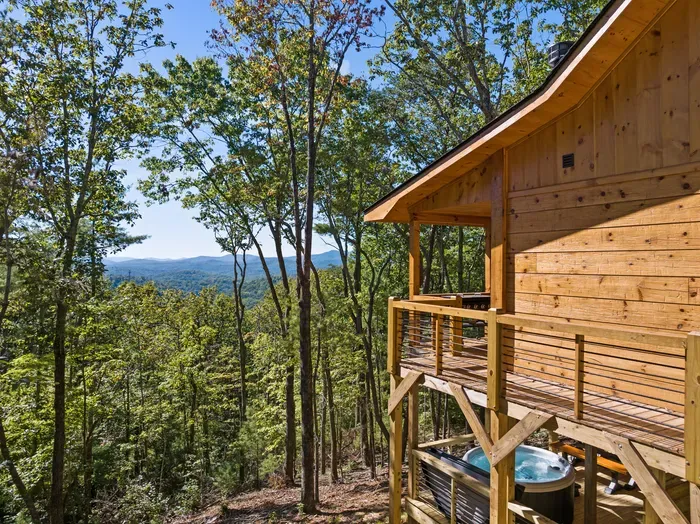Secluded cabin deck with hot tub and scenic mountain forest views