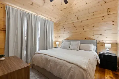 Cozy wood-lined bedroom with plush bed and serene cabin charm. Second Bedroom. Brooklyn Bed Co king bed, hypoallergenic luxury linens
