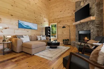 Cozy cabin-style living room with stone fireplace and soaring wood walls