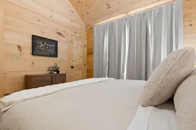 Cozy wood-paneled bedroom with plush bed and restful cabin charm. Second bedroom, plush hypoallergenic bedding, Brooklyn Bed Co King Bed.