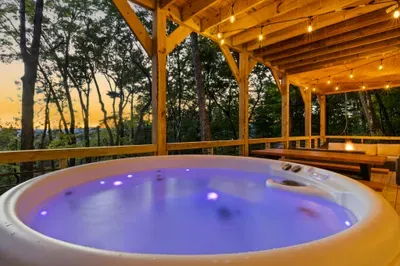 Relax in the hot tub under string lights on a serene wooded deck