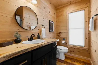 Rustic-modern bathroom with wood walls, live-edge vanity, and bright window. Hall Bathroom
