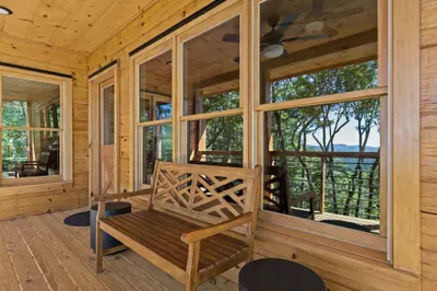 Covered wood porch with bench seating and peaceful water-view reflections