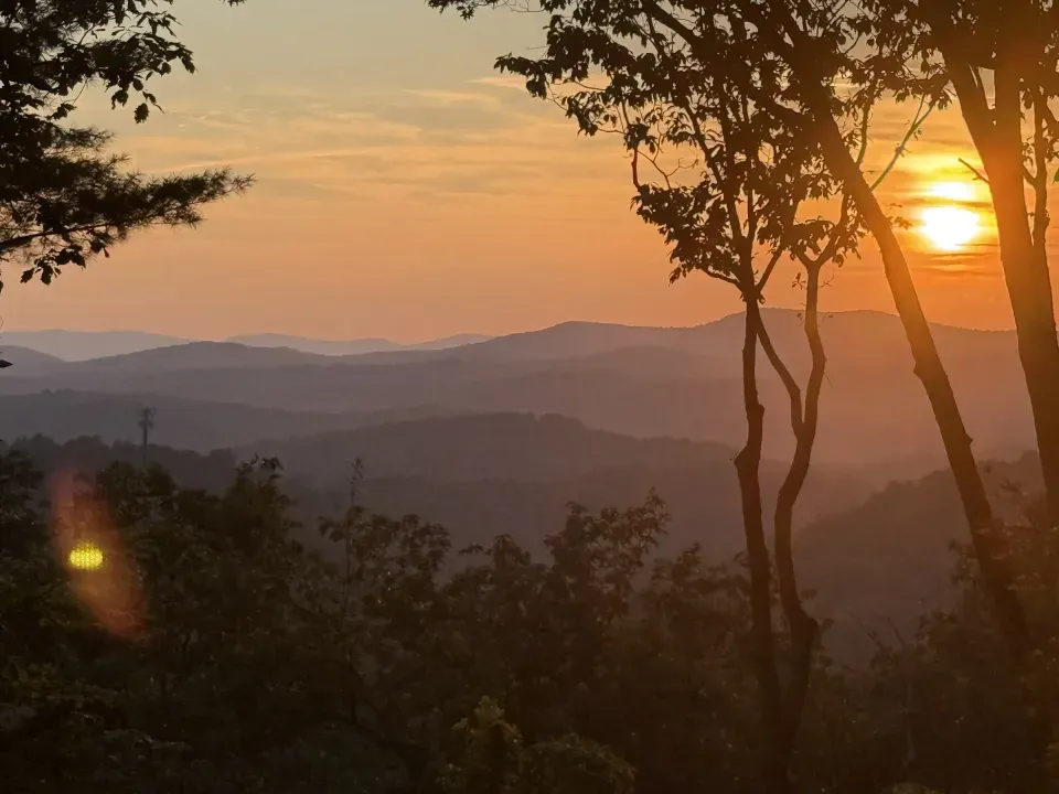 Sunset over layered Blue Ridge Mountain ridgelines, seen through the trees from the cabin in Cherry Log, Georgia