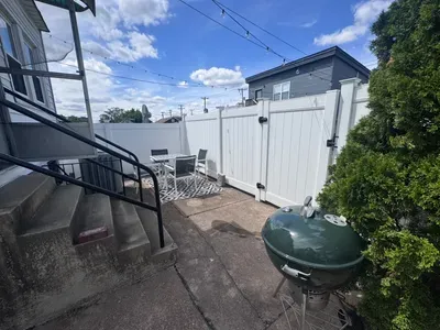 Backyard patio with table and chairs and charcoal grill