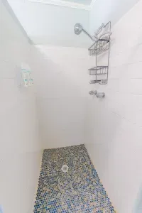 Walk in shower with tiled flooring mounted dispensers and metal storage rack providing guests