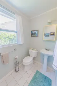Bathroom with pedestal sink toilet and window lighting arranged for straightforward daily use.
