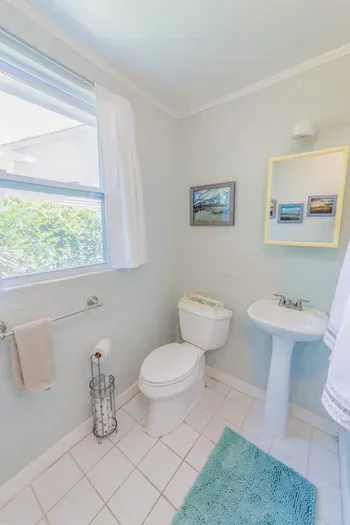 Bathroom with pedestal sink toilet and window lighting arranged for straightforward daily use.