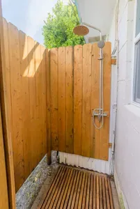 Outdoor Shower Oasis: Refresh in this charming wooden shower set among lush greenery!