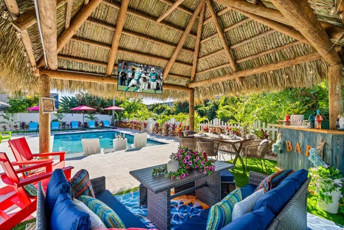 The tiki hut with bar and seating offers a shaded escape where you can enjoy snacks, drinks, and conversation just steps from the pool.