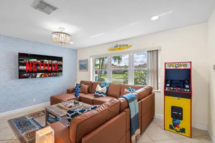 This bright open-concept living room is the social hub of the home, blending comfy seating, a pool table, and an arcade game so everyone in your group has something fun to do.