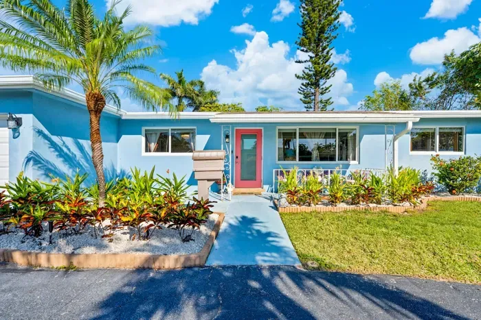 The home's inviting exterior welcomes you to a peaceful South Florida retreat, surrounded by lush landscaping and privacy.