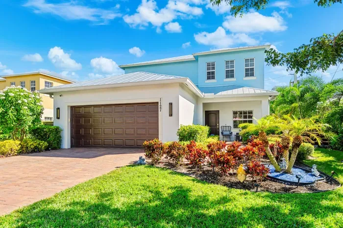 Front view of this stunning newly built home with tropical landscaping leading to the front door with some outdoor seating, perfect for those that like to enjoy the greenery before entering the stunning home.