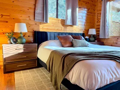 Cozy wood-lined bedroom with plush bedding and warm natural light