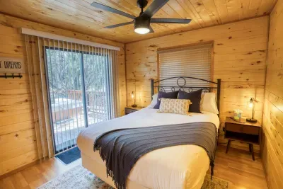 The primary bedroom has a queen bed and a door to the deck with hot tub.