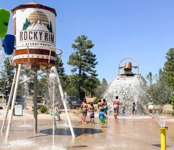 Family-friendly splash pad with tipping buckets amid pines—steps from cabins.