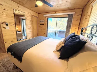 Cozy cabin bedroom with deck access, full-length mirror, and tranquil nature views.