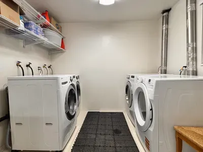 Spacious shared laundry room with multiple washers, dryers, and storage