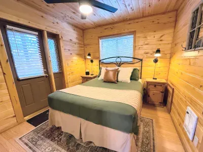 Cozy cabin bedroom with queen bed, sconces & private door