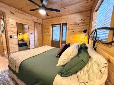 Cozy cabin bedroom with plush queen bed, ceiling fan, and private door