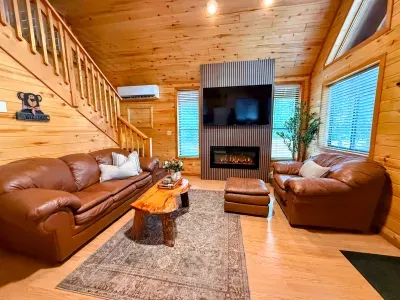 Cozy cabin living room with fireplace, TV, and warm rustic charm